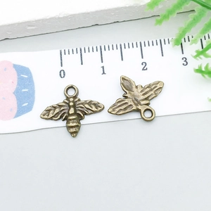 Makro-Detail von zwei Vintage-Bronze-Bienenanhängern mit geprägten Flügeln und Ösen