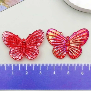 Makro-Detail von roten und schillernden Acryl-Schmetterlingsanhängern für DIY-Schmuck