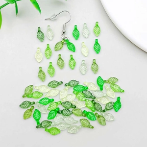 Macro shot of green acrylic leaf charms with drill holes for DIY jewelry making crafts