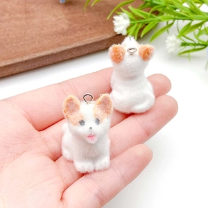 Close-up of handmade flocked resin puppy pendants showing soft texture and small scale