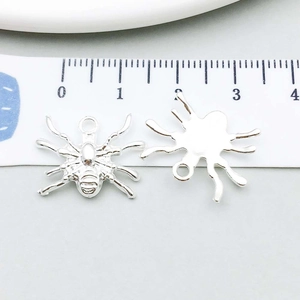 Detail of silver spider charms for DIY jewelry with measurement scale for size reference