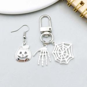 Close-up of Halloween charms including silver pumpkin earrings and a skull hand keychain