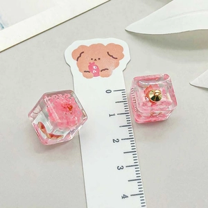 Macro view of 1.5cm pink resin cube charms with dried flowers and gold metal loops