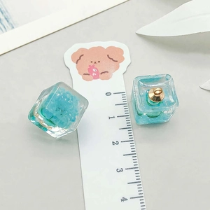 Detailed macro view of resin cube pendants with blue dried flowers and measurement scale