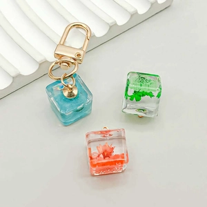 Close-up of handmade resin square pendants with preserved dried flowers and gold metal clasps