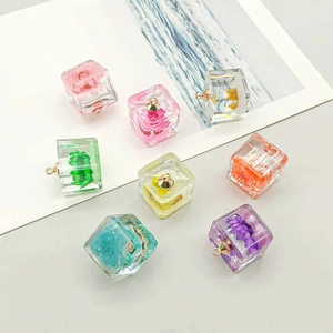 Close-up of luminous resin cube pendants featuring colorful dried flowers and metal hooks