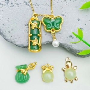 Macro detail of Chinese green jade pendants with gold accents and pearl on stone surface