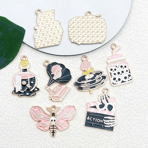 Detail of pink and black gothic enamel charms including gramophone and potion bottle