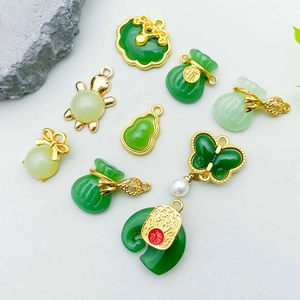 Chinese green jade-like pendants with gold-plated charms including gourd and money bag