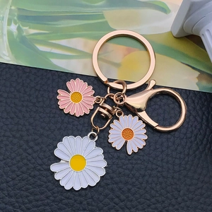 Detail der Gänseblümchen-Schlüsselanhänger mit Goldkarabiner und Emaille-Blumen
