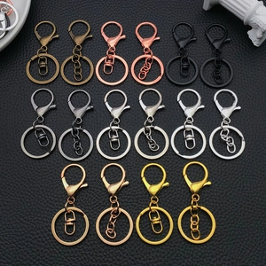Flache Ansicht bunter Karabiner-Schlüsselanhänger-Kits mit Ringverbindern auf schwarzem Leder