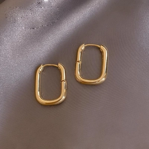 Pendientes de aro rectangulares dorados pulidos sobre elegante seda gris