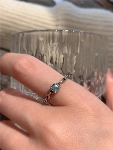 Détail d'une bague chaîne en argent s925 avec zircon bleu sur la main d'une femme
