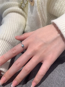 Gros plan sur la bague torsadée en argent S925 avec une pierre bleue au doigt