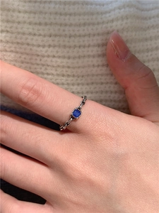 Détail d'une bague chaîne en argent S925 vintage avec une pierre précieuse bleue carrée