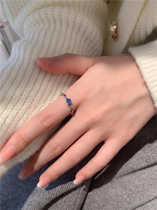 Détail d'une bague chaîne en argent avec zircon bleu carrée portée au doigt