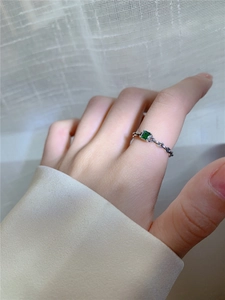 Détail d'une bague chaîne en argent s925 avec un zircon émeraude carré porté à la main