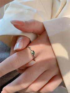 Détail de la bague en zircon vert émeraude avec anneau argenté au design de chaîne tissée