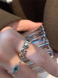 Gros plan de bagues en argent s925 avec zircon émeraude, motifs fleurs et chaînes au doigt