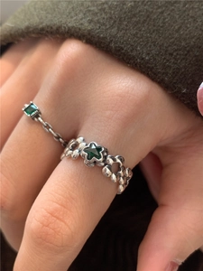 Détail de la bague chaîne en argent s925 avec zircon vert en étoile sur l'anneau relié