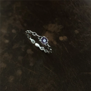 Détail macro d'une bague chaîne argentée avec une pierre de zircone violette sertie