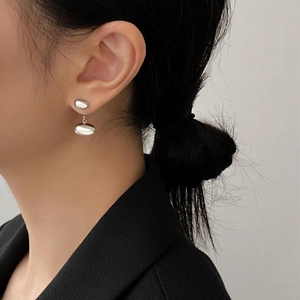 Minimalist silver oval bean earrings featuring a high-polish mirror finish on a model