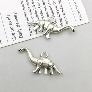 Close-up of two dinosaur shaped alloy charms with detailed carving for DIY jewelry making