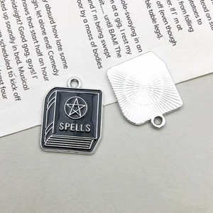 Macro detail of alloy book pendant with black enamel finish and SPELLS engraving