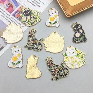 Detailansicht der Emaille-Anhänger mit Katzenmotiv und floralen Mustern auf Gold
