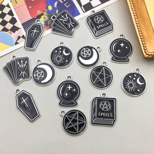 Close-up of gothic enamel charms featuring spell books and tarot symbols for DIY jewelry