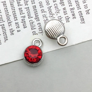 Macro detail of silver alloy round pendants with faceted red rhinestones for DIY jewelry