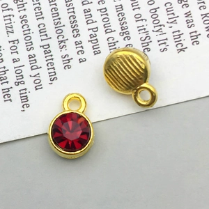 Close-up of double-sided gold alloy pendants with red faceted stone and textured back