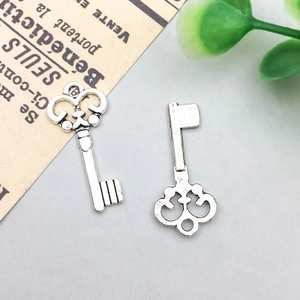Detailed view of two vintage silver alloy key charms with intricate hollow patterns for DIY