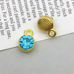 Detail of round gold-plated charms with sky blue crystals and striped texture backings