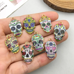 Bunte Emaille-Totenkopf-Anhänger mit vergoldetem Rand für DIY-Schmuck in der Hand gehalten