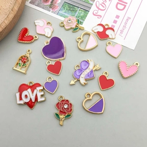 Flat lay of colorful enamel heart and rose charms with gold wings for DIY jewelry making