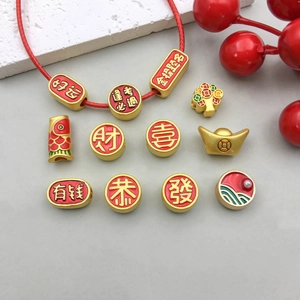 Close-up of gold DIY jewelry charms with red enamel and lucky Chinese characters