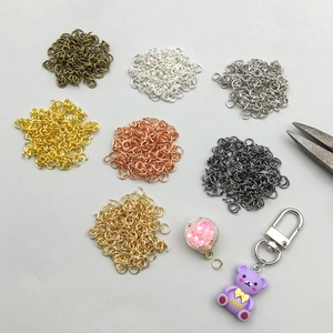 Vista macro di anellini aperti multicolore e ciondolo a forma di orsetto per gioielli