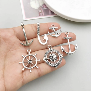 Antique silver marine jewelry set with anchor, rudder and compass charms held in hand