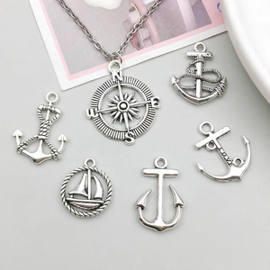 Macro detail of antique silver nautical charms with anchors and compass for DIY jewelry making