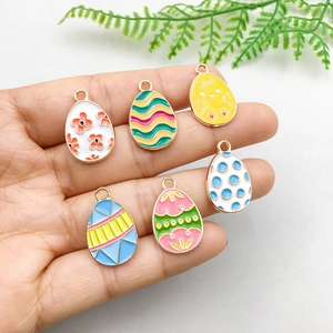 Set of 6 colorful enamel Easter egg pendants with floral patterns held in hand