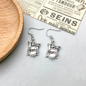Detail of vintage silver drum set earrings featuring engraved musical notes and staff