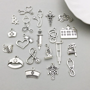 Detailed macro shot of vintage silver alloy medical charms including a stethoscope