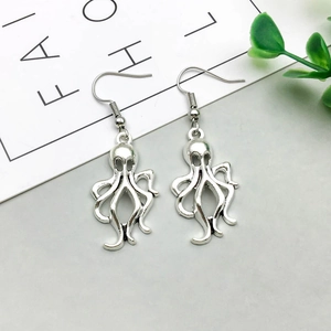 Detail of silver alloy octopus hook earrings featuring an intricate hollow design