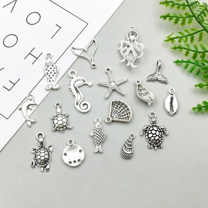 Macro detail of antique silver ocean charms including seahorse, turtle, and starfish shapes