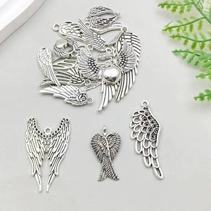 Gros plan de breloques ailes d'ange en argent antique avec détails de roses et de coeurs