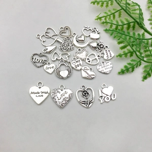 Flat lay of vintage silver alloy heart pendants with engraved messages for DIY jewelry