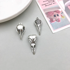 Detailed view of antique silver bird skull pendants with intricate engraved textures