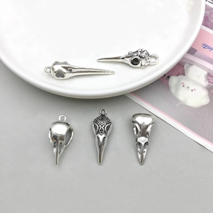 Macro shot of antique silver bird skull pendants with ornate engravings for jewelry making