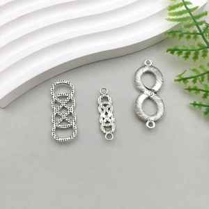Makro-Detail von antiken Silber-Infinity- und Geometrieanhängern für DIY-Schmuck